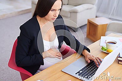 Concentrated pregnant businesswoman using laptop Stock Photo