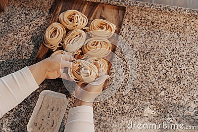 Crop housewife preparing homemade rolled tagliatelle pasta Stock Photo