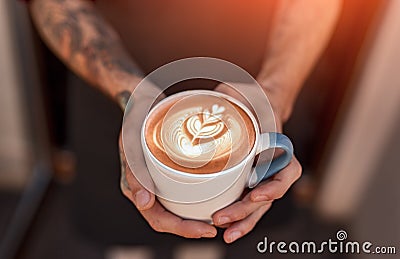 Barista holding cup of coffee with latte art Stock Photo