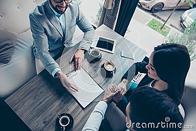 High angle cropped photo of family making a deal with lawyer about their business in cafe with cups of coffee. Men is going to si Stock Photo