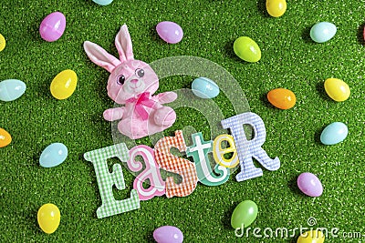 High angle of plush bunny and Easter letters banner with plastic Easter eggs Stock Photo