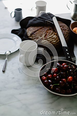 High-angle shot of a bowl of cherries and a freshly baked bread in the kitchen Stock Photo