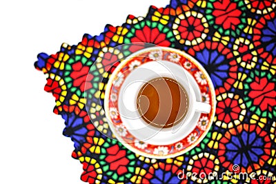 High angle shot of a cup of tea on a traditionally designed placemat on a white surface Stock Photo