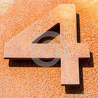 High angle shot of the number 4 on an orange stone surface Stock Photo