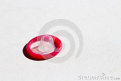 High angle shot of a pink condom on a white textured surface Stock Photo