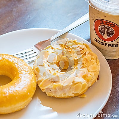 High angle shot of a plate of a plain donut and a peanut donut next to a cup of iced coffee Editorial Stock Photo