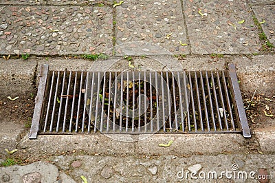 High angle shot of a rusty metal rain drain on a sidewalk Stock Photo