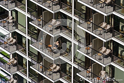High angle shot of similar apartment balconies with outdoor furniture and a man tanning Stock Photo