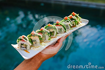 High angle shot of someone holding a tray of sushi over the pool Stock Photo