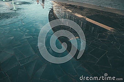 High angle shot of a stone wet surface with a reflection of a round building Stock Photo