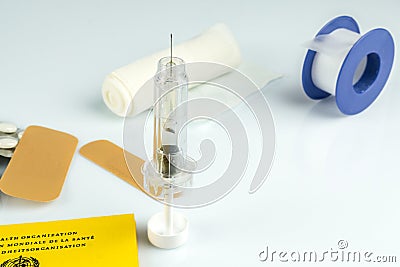 High angle shot of a syringe, bandaids, plastic tape, and pills on a white surface Stock Photo