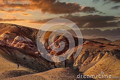 High angle shot of a tourist standing in front of massive red mountains in Kyzyl-Chin valley, also called Mars valley. Beautiful Editorial Stock Photo