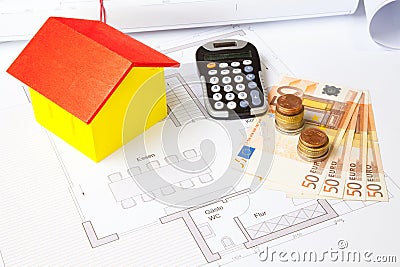 High angle shot of a toy house, banknotes, coins, a calculator and house plans- real estate concept Stock Photo