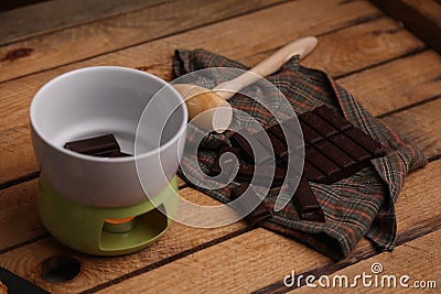 High angle shot of a wooden small mallet near a bar of dark chocolate and a bowl of chocolate Stock Photo