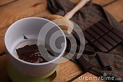 High angle shot of a wooden small mallet near a bar of dark chocolate and melted chocolate Stock Photo