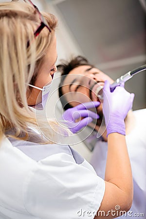 High angle view of a beautiful young female dentist polishing or repairing dental cavity on male patient`s teeth Stock Photo