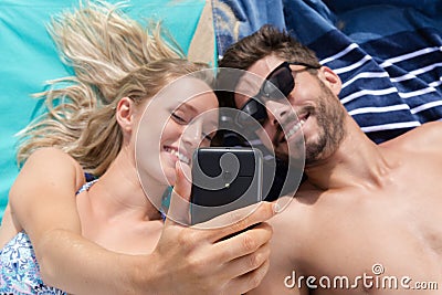 High angle view couple layed on beach taking selfie Stock Photo