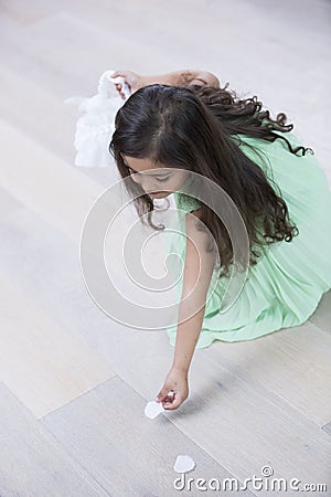 High angle view of girl picking up flower petals from floor at home Stock Photo