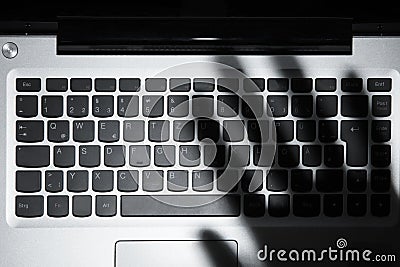 Shadow Of Person`s Hand Falling On Laptop Keypad Stock Photo