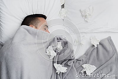 Ill man in bed surrounded by used tissues Stock Photo