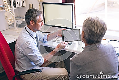 Male doctor discussing over digital tablet with senior woman Stock Photo