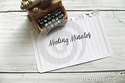 High angle view of miniature typewriter and paper written with Meeting Minutes on white wooden background Stock Photo