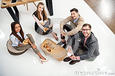 high angle view of smiling multiethnic business people with pizza looking at camera Stock Photo