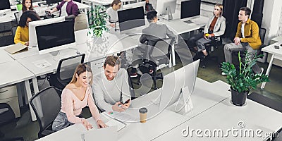 High angle view of smiling young businessman and businesswoman talking while working with colleagues Stock Photo