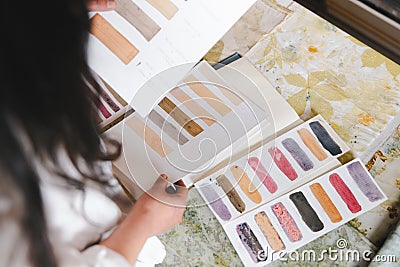 High angle view of a textile artist looking at color palette for print on natural fiber clothing. Flower dye crafts. Stock Photo