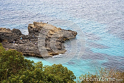 High angle view of tourists exploring rocky cliff by sea in scenic island Stock Photo