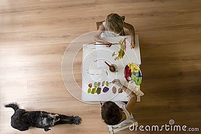 Children painting on table with dog lying on floor Stock Photo