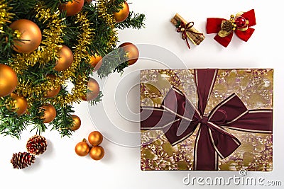 High angle view of a wrapped gift, a collection of Christmas ornaments and a plastic pine tree on a white background. Stock Photo