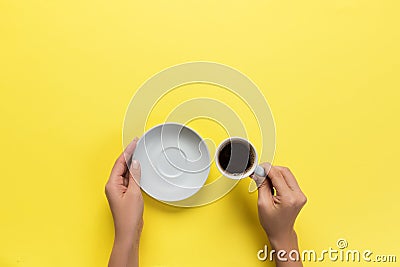 High angle of woman hands holding coffee cup on yellow background Minimalistic style. Flat lay, top view isolated Stock Photo