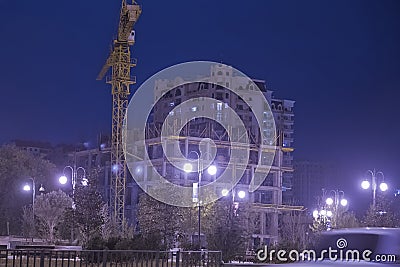 High buildings under construction with cranes at evening . Lightening multi-storey buildings under construction and cranes at nigh Editorial Stock Photo