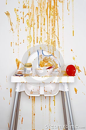 High chair with bowl spoon jar and stains of baby food view from above Stock Photo