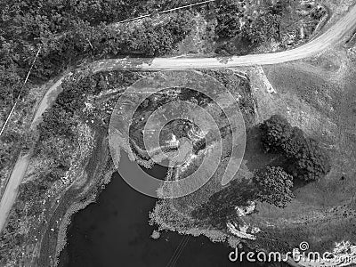 High drone aerial down onto lines formed by pipes, a road, the plant lined waters edge, and power lines Stock Photo