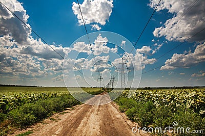 High electricity pillars on country road under blue sky clouds Stock Photo