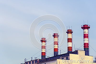 High factory exhaust pipes against a blue sky, urban air pollution Stock Photo