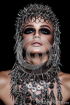 High fashion beauty model with metallic headwear and dark makeup and blue eyes on black background Stock Photo