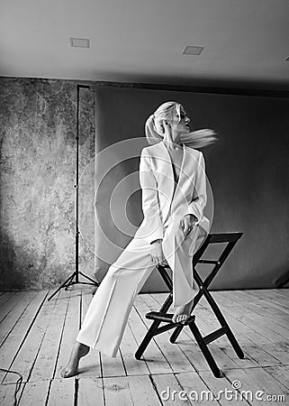 High Fashion blond woman in white suit. Elegant Style model. Dynamic shot in Photo studio shooting Stock Photo