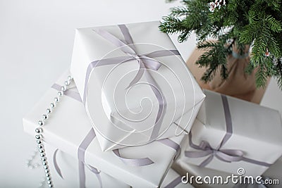 High-key modern Christmas card with pile of gift boxes wrapped in white paper and pinetree at background Stock Photo