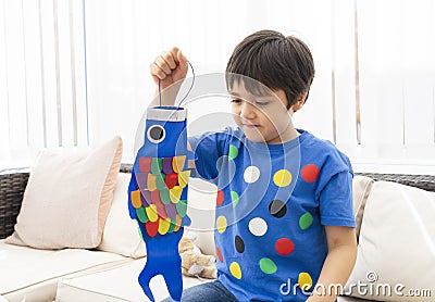 High key Portrait happy kid stay at home making coloufull Koinobori Carp streamers, Child boy doing Japanese fish kite in sunny Stock Photo