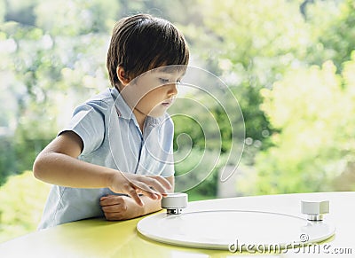 High key portrait of school kid playing game in playroom with blurry natural background, Child holding bottom game with wondering Stock Photo