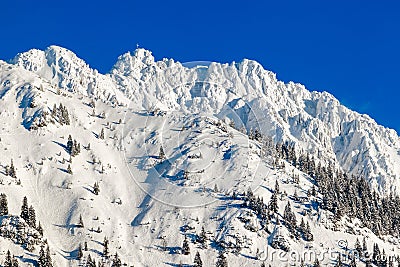 High mountain with summit cross under deep snow in winter. Rauhhorn, Allgau, Bavaria in Germany. Stock Photo