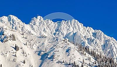 High mountain with summit cross under deep snow in winter. Rauhhorn, Allgau, Bavaria in Germany. Stock Photo
