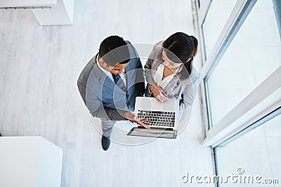 A high performing team needs high performing technology. High angle shot of a young businessman and businesswoman using Stock Photo