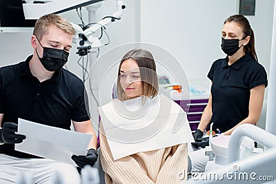 High-qualified dentist shows the young female patient an X-ray of the teeth in the dental chair at modern clinic. Stock Photo