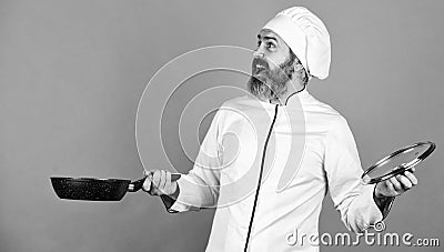 High quality frying pan. Bearded man cook white uniform. Cooking like pro. Regular cooking. Easy tasty meal prepared at Stock Photo