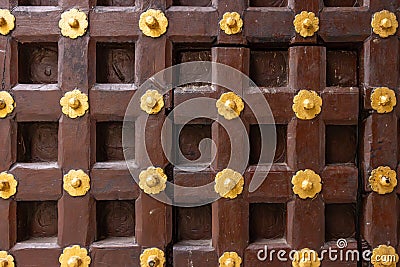 High res antique dark brown polished wooden door with geometric symmetrical square and golden rosettes decoration close up Stock Photo