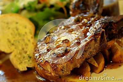 High resolution grilled `kuro buta`pork ribs and black pepper sauce served with potato wedges,bread and salad Stock Photo